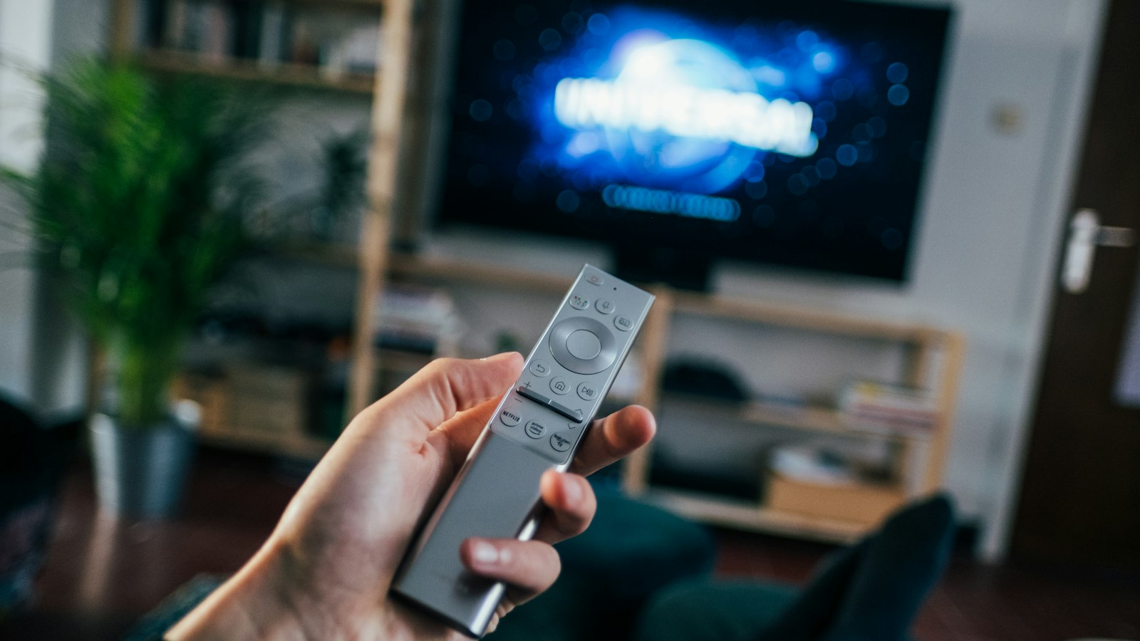 Mano con mando, televisor en una estantería